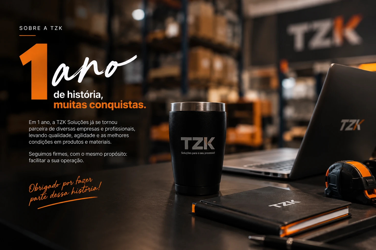 1 ano de história, muitas conquistas — copo, caderno e itens TZK sobre a mesa, celebrando o primeiro ano da Tzk Soluções. Obrigado por fazer parte dessa história!